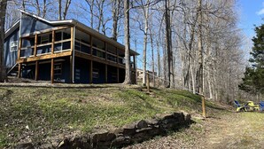 A two-story building with a balcony on the upper floor, surrounded by trees. - Lake Daze, Blue Cottage <1mile to Jamestown Marina with space to trailer boat. (Jamestown)