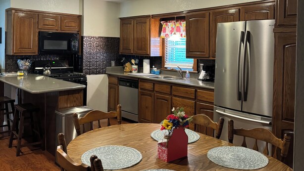 A modern kitchen with wooden cabinets, stainless steel appliances, and a dining area with a wooden table and chairs.