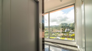 Un interno moderno con un'ampia porta scorrevole in vetro che si apre su un balcone con vista panoramica su una città e sulle montagne.