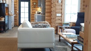 Een gezellig interieur van een blokhut met een zithoek, keuken en eethoek.
