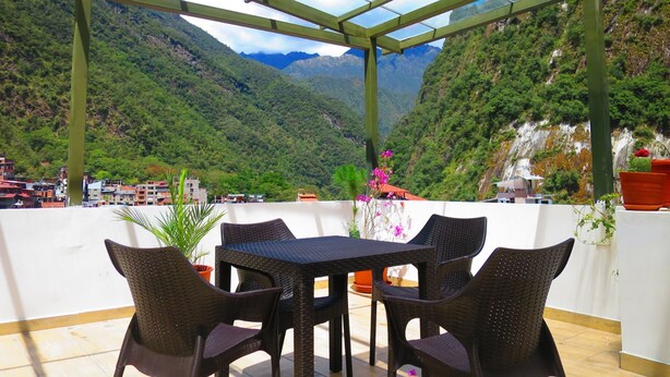 Un espacio de estar al aire libre techado, con una mesa y sillas, con vistas a un paisaje montañoso.