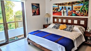 A hotel room with a bed, a nightstand, a lamp, and a painting on the wall.