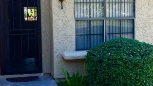 A house with a black door, a window with bars, and a small stone ledge.
