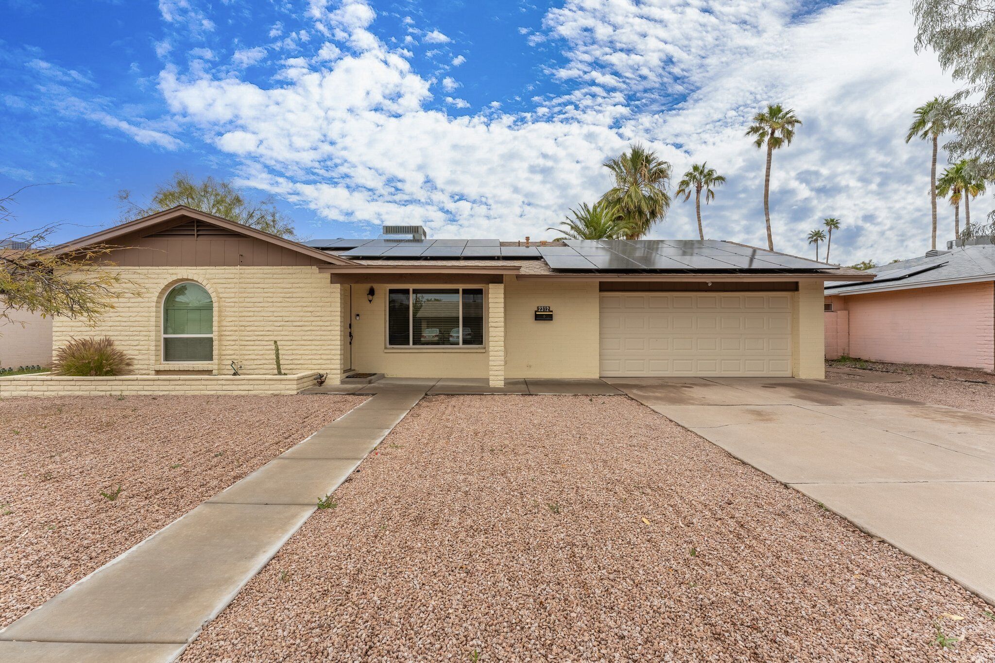 A single-story house with a garage, a driveway, and a gravel lawn.
