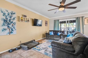A living room with a ceiling fan, a TV, a couch, a coffee table, and a painting on the wall.