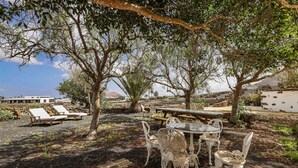 Un jardín con mesa y sillas, una terraza de madera y sillones de descanso.