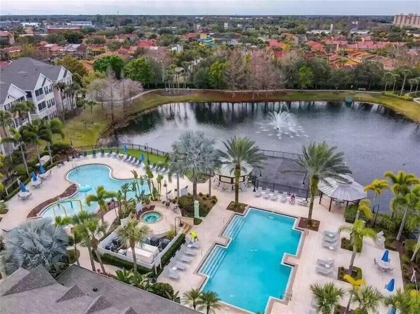 Relax by the resort's central pool surrounded by lounge areas and palm trees.