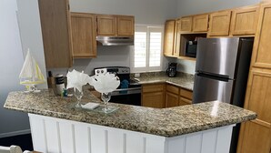 Una cocina con armarios de madera, un refrigerador de acero inoxidable y una encimera de granito.