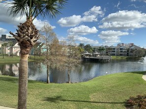 Overlooking a serene lake, this lakeside retreat offers a peaceful atmosphere and a bridge connecting to a building with a green roof.