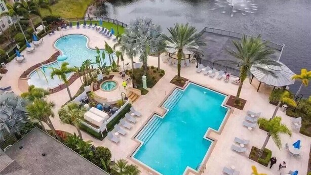 Un resort con varias piscinas, palmeras y vistas a un cuerpo de agua.