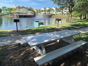 A park with a picnic table, a pond, and a bridge in the background.