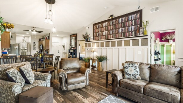 Een ruime woonkamer met leren banken, een eethoek en een grote boekenkast.