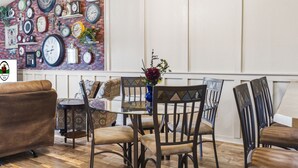 Een eethoek met een met klokken versierde bakstenen muur, een glazen tafel en houten stoelen.