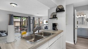 A modern kitchen with two stainless steel sinks, a coffee machine, and a dining area with a table and chairs. - Private Balcony, Fireplace & King Bed | Near Golf & Entertainment in Branson (Branson)