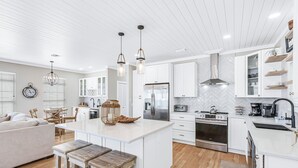 A modern kitchen with white cabinetry, a central island, and wooden bar stools.