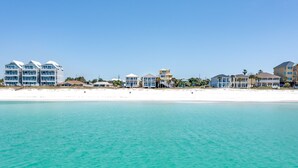 A beachfront hotel with multiple buildings, a sandy beach, and clear turquoise water.