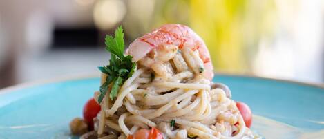 A plate of spaghetti with shrimp and cherry tomatoes.