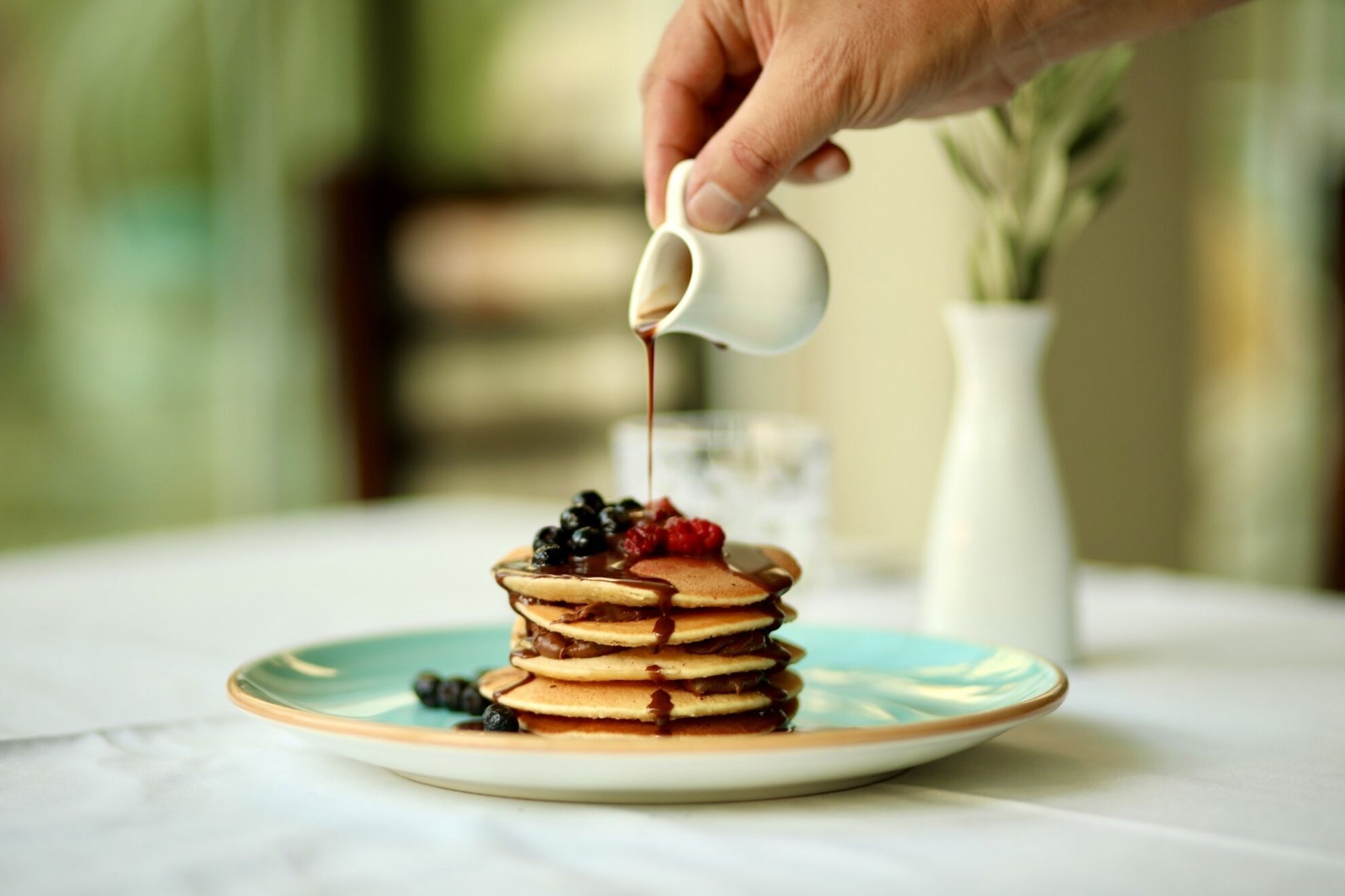 A stack of pancakes with syrup and berries on a plate.