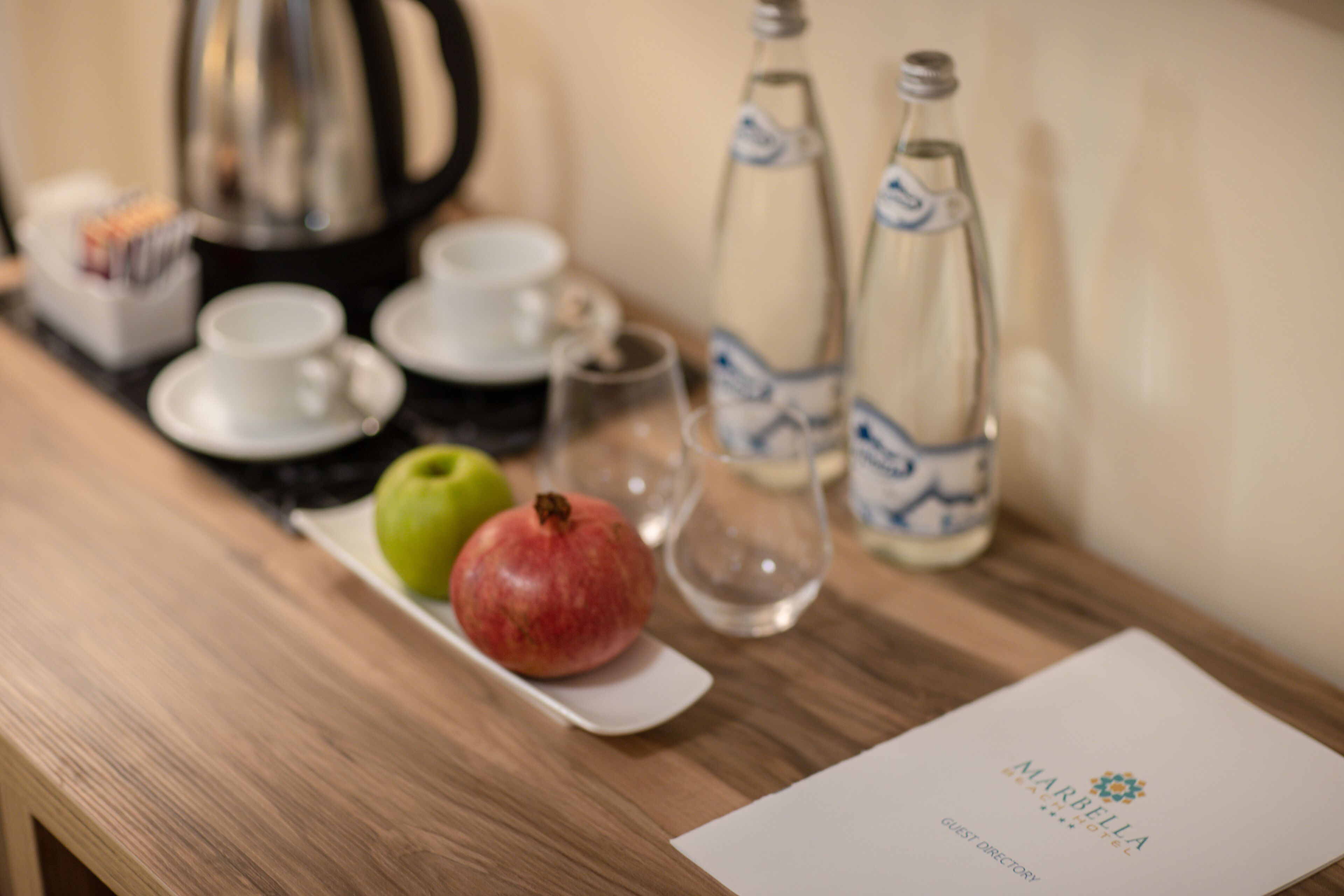 Ein Tisch mit einer Granatapfel, einem grünen Apfel und zwei Wasserflaschen.