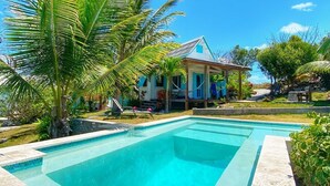 Piscina rectangular con agua cristalina azul, rodeada por una terraza de piedra.