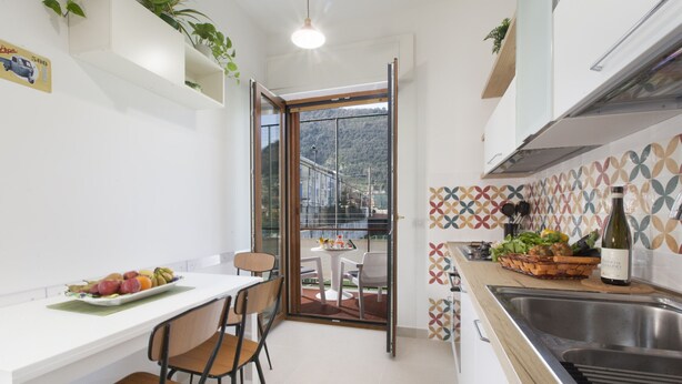 Una cucina compatta con angolo ristoro, lavello e vista su un balcone.