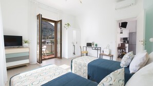Camera d'albergo con due letti, televisione, scrivania e vista sull'esterno.