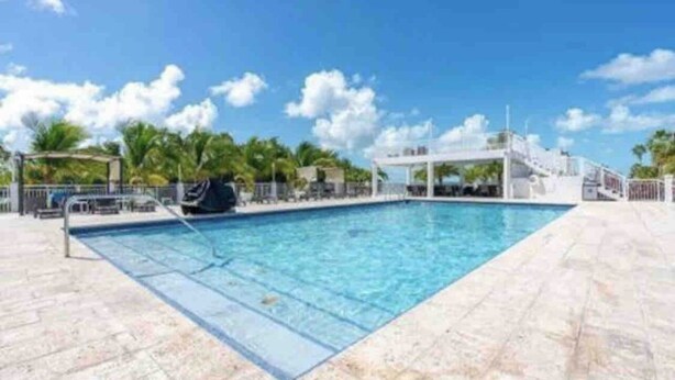 A rectangular swimming pool with clear blue water, surrounded by a tiled deck. - Relax at Key Largo (Key Largo)