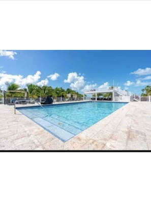 A rectangular swimming pool with clear blue water, surrounded by a tiled deck.