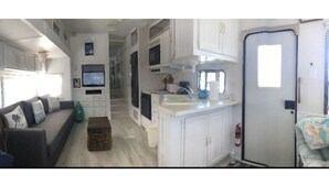 A compact RV interior with a kitchenette, a living area with a sofa, and a small dining table. - Relax at Key Largo (Key Largo)
