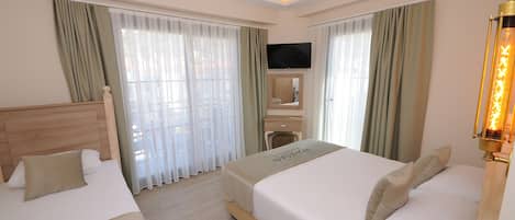 A hotel room with two beds, a flat-screen TV, a wooden headboard, and a bedside table with a lamp.