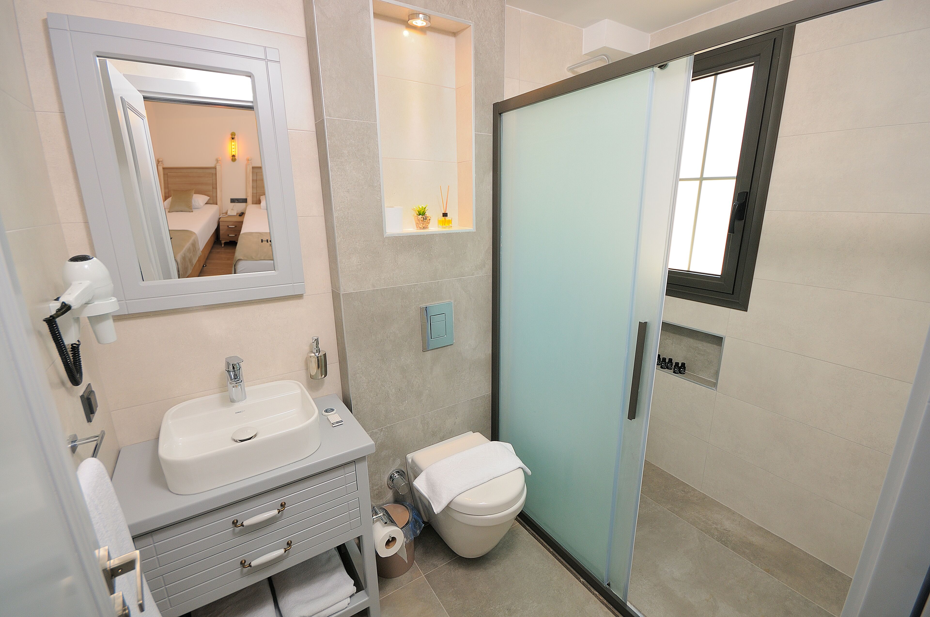 A modern bathroom with a sink, mirror, toilet, and a shower area.