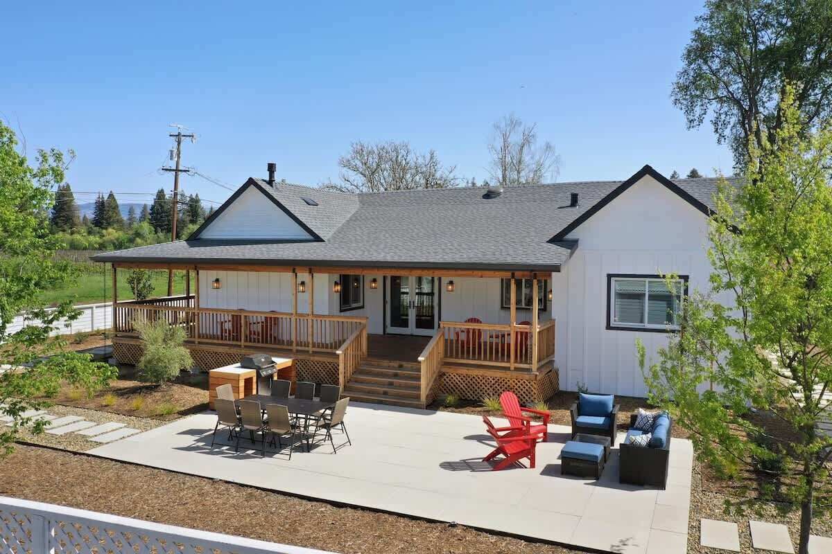 A house with a covered patio, outdoor seating, and a deck.