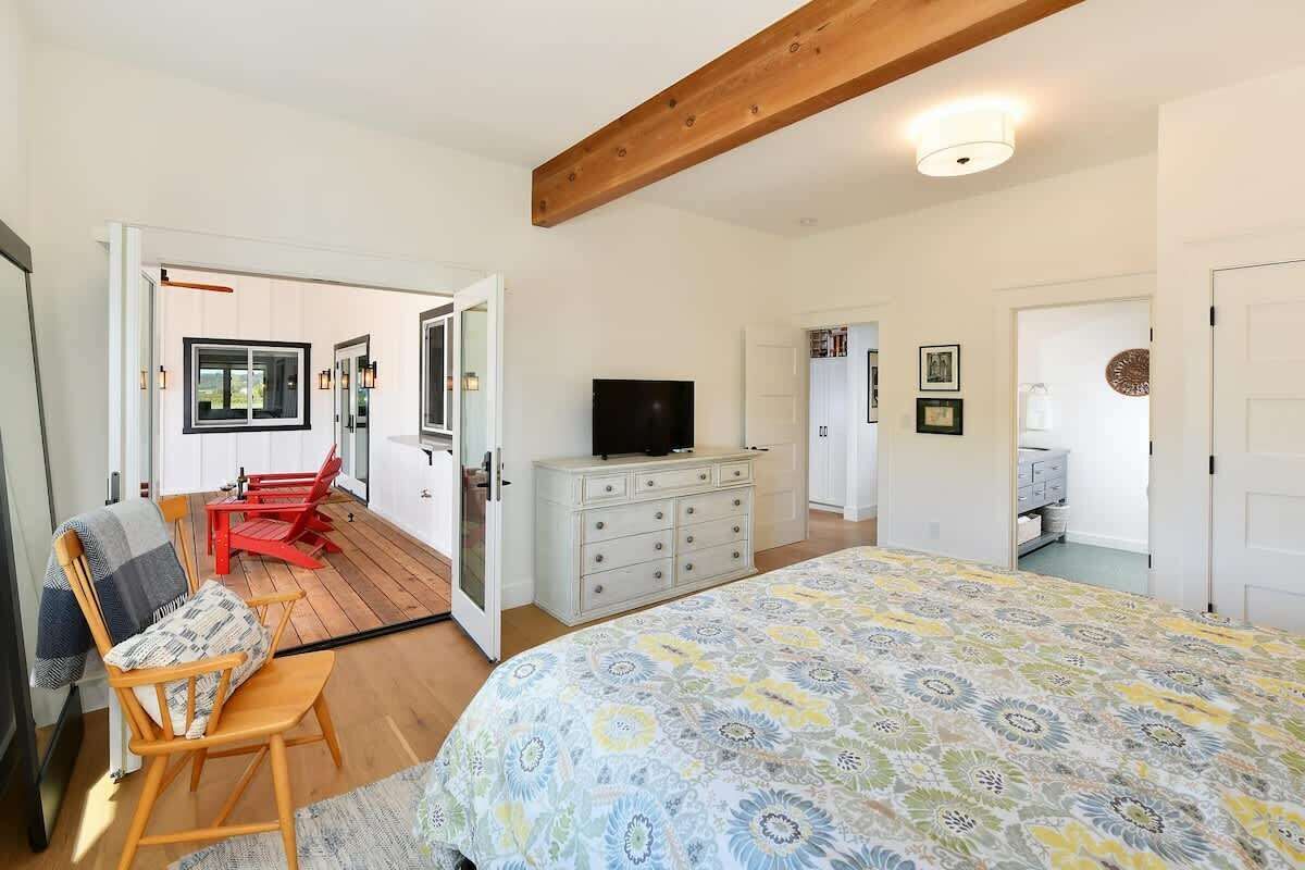 A bedroom with a bed, a TV, a dresser, and a red chair.