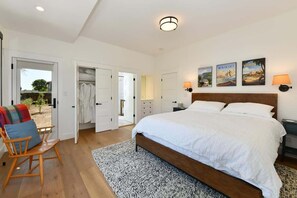 Un dormitorio con una cama grande, una silla de madera, un armario y una puerta que da a un espacio exterior.