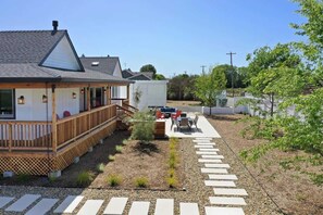 A residential property with a wooden deck, outdoor seating, and a garden pathway.