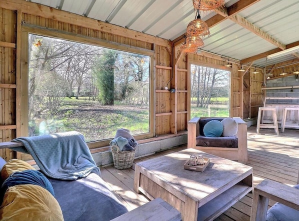L’intérieur d’un chalet en bois, avec une grande fenêtre, un canapé, un fauteuil et une table.