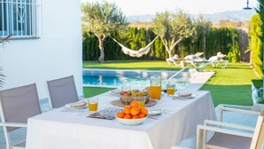 Ein Esstisch draußen mit Blick auf Pool und Garten.