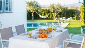 A dining table set outdoors with a view of a pool and garden. - El Refugio de Paco Alhaurín de la Torre by Ruralidays (Málaga)