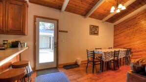 Interior em madeira com área de jantar, banquetes de bar e uma porta que dá para o exterior.