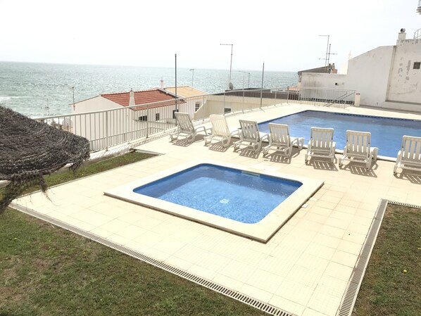 A rooftop pool with a view of the sea, surrounded by white lounge chairs and a small garden area. - Charming Sea View Flat w/Pool, 20 meters from the Beach (Albufeira)