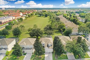 Un quartier résidentiel avec des maisons, un grand espace vert et une vue lointaine sur les gratte-ciel d’une ville.