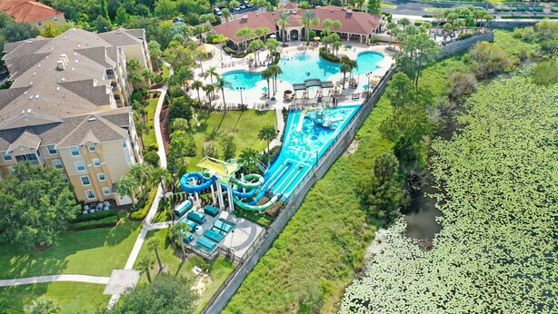 Vue aérienne d’un complexe hôtelier doté de plusieurs piscines, de toboggans aquatiques et d’un grand lac.