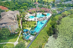 Vue aérienne d’un complexe hôtelier doté de plusieurs piscines, de toboggans aquatiques et d’un grand lac.