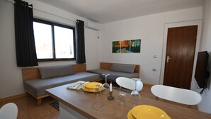 Ein modernes, kompaktes Wohnzimmer mit Sofa, Esstisch und Stühlen.