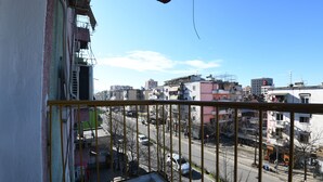Ein Balkon mit Metallgeländer mit Blick auf eine Straße mit Gebäuden und Autos.