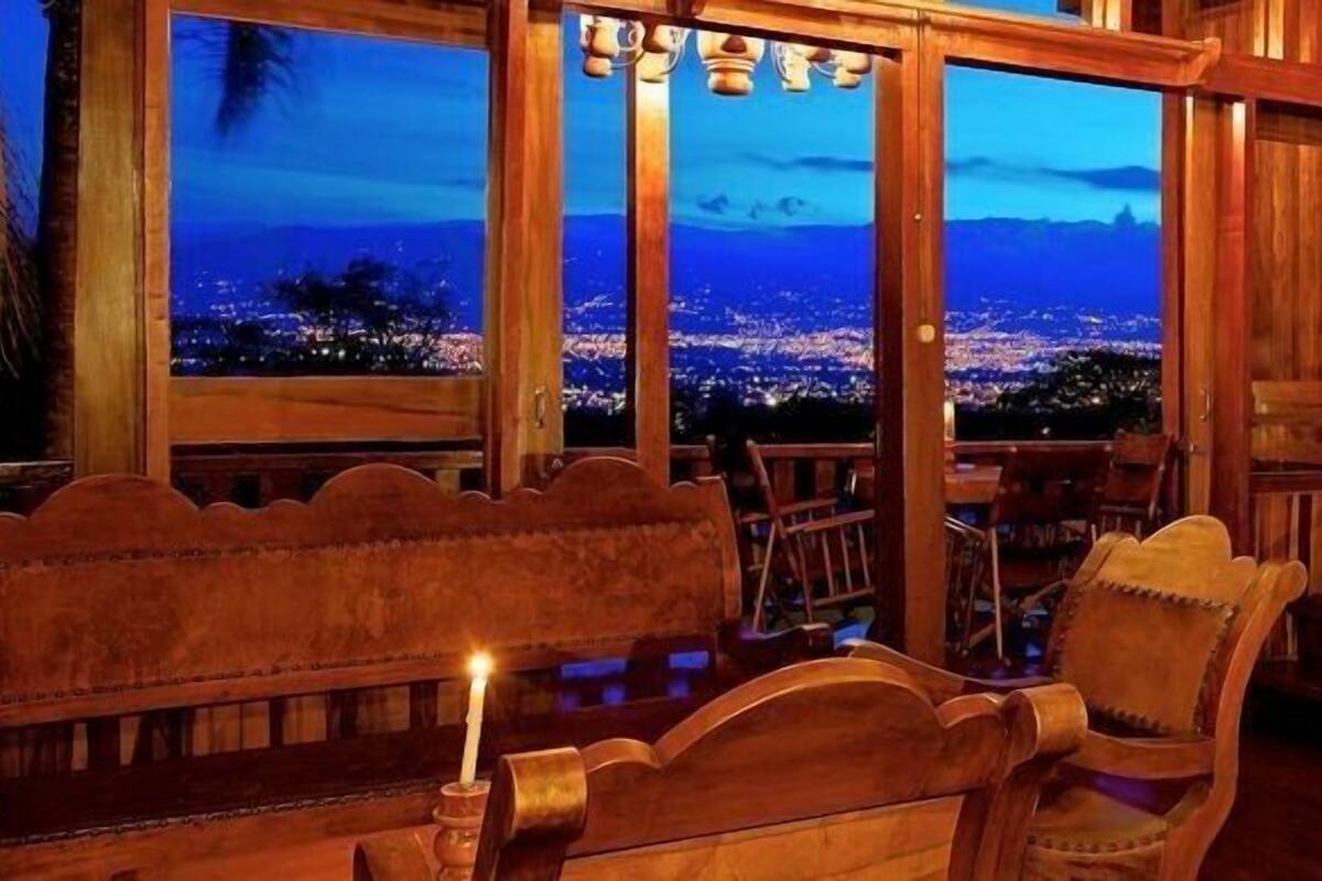 Interior em madeira com vista para a cidade ao entardecer.