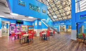 A spacious indoor area with a high ceiling, wooden flooring, and red chairs.