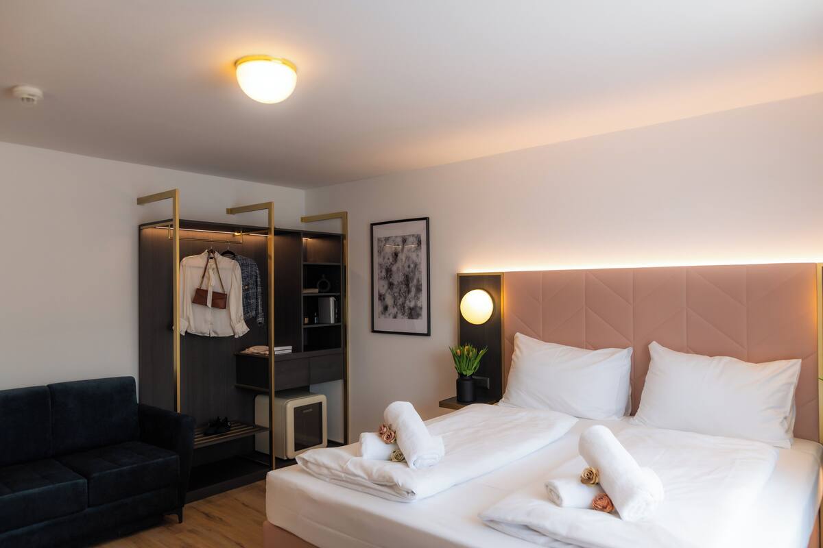 A hotel room with a bed, a wardrobe, a small desk, and a couch.