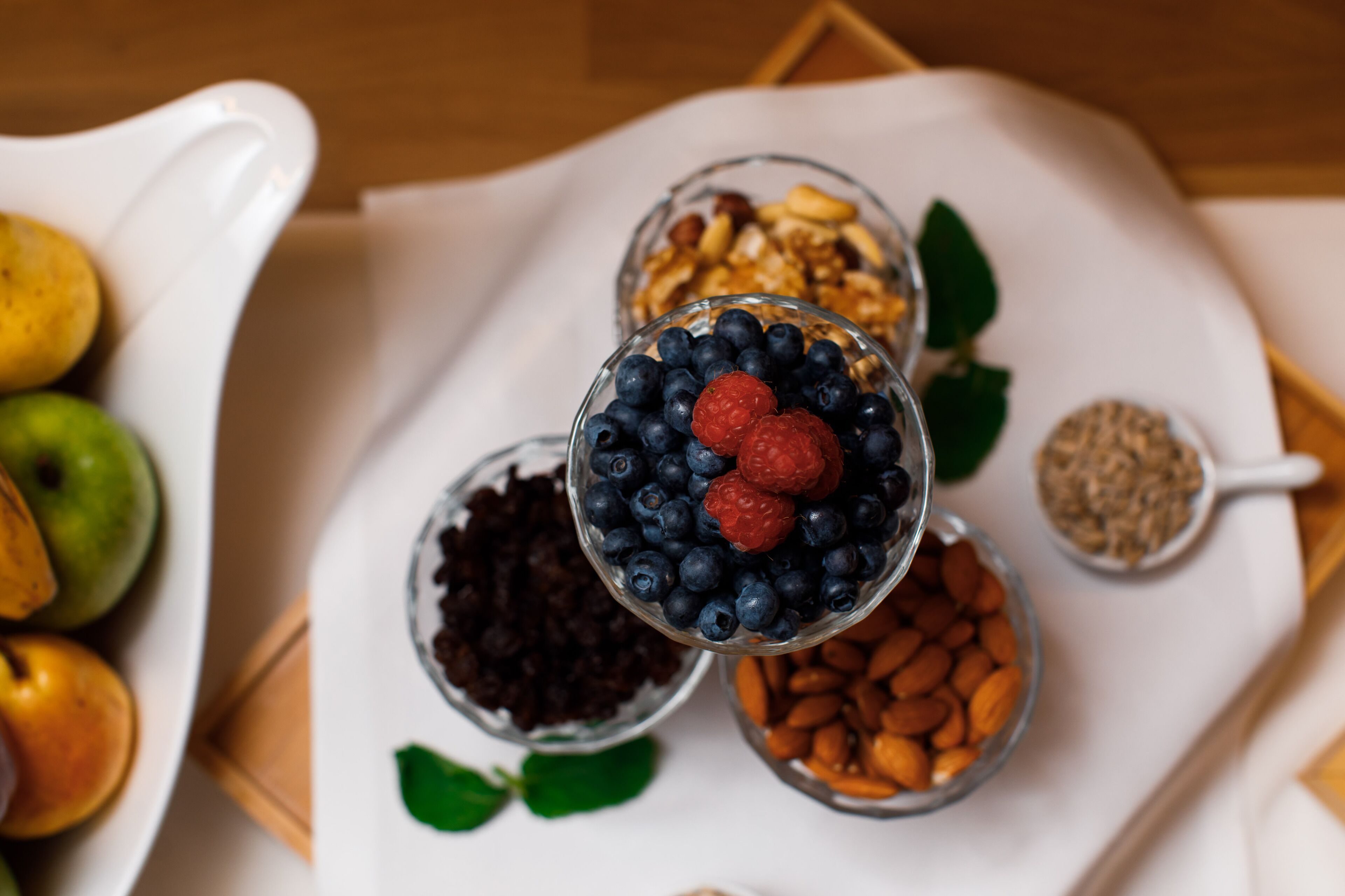 Una bandeja con diversos alimentos, como frutas, nueces y granos.