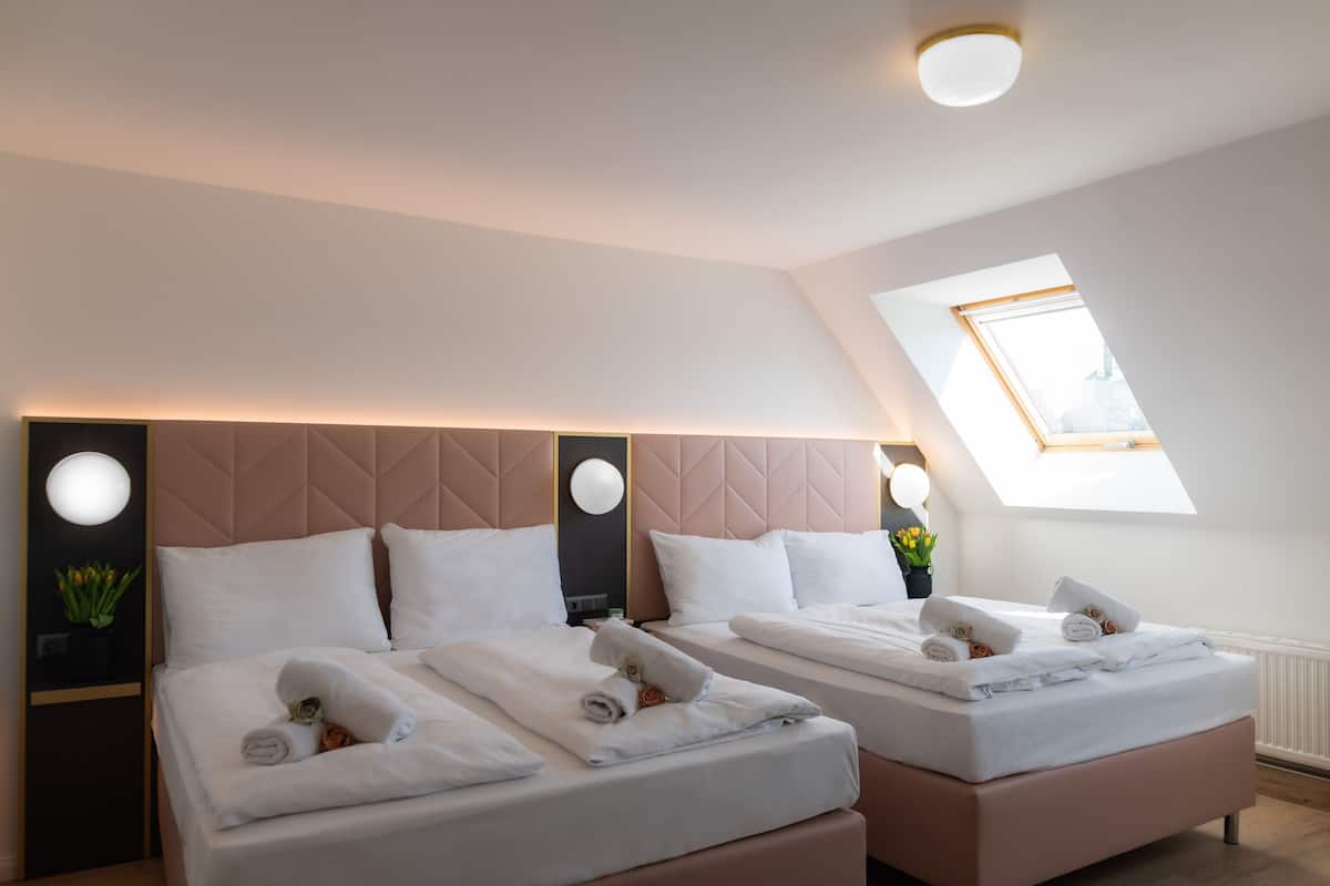 A hotel room with two beds, each with neatly folded towels and a headboard.